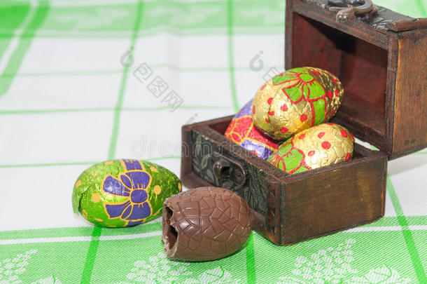 巧克力复活节彩蛋放在木制棺材里，放在厨房桌布上