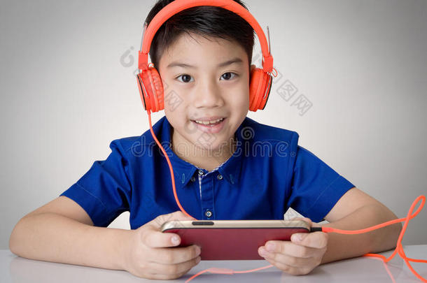 亚洲男孩准备耳机和<strong>玩手机</strong>