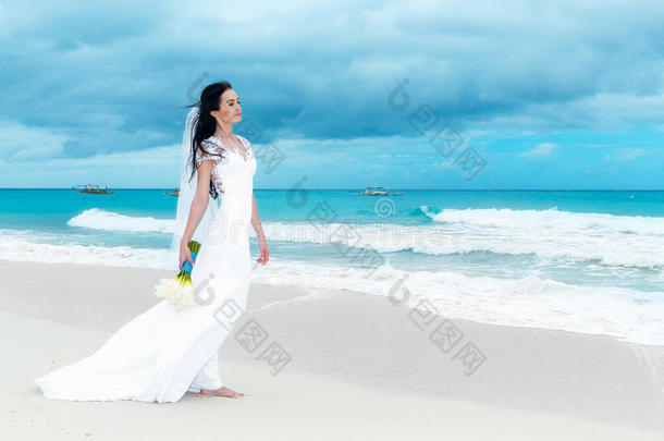 美丽的未婚妻穿着白色婚纱，白色的<strong>大火</strong>车和婚礼花束站在海边