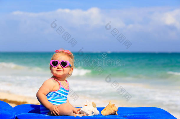海滩上带贝壳的可爱小女孩