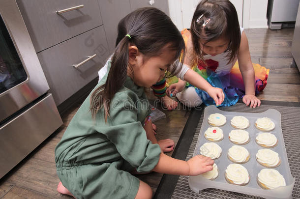 亚洲幼儿在厨房装饰纸杯蛋糕