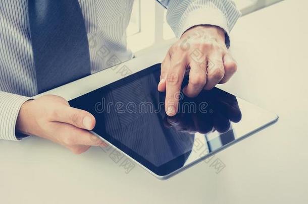 商人手触摸平板电脑屏幕在桌子上