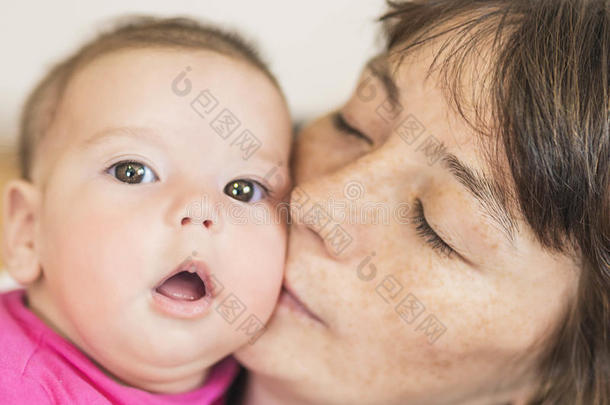 可爱的母亲亲吻她的小新生女孩的肖像