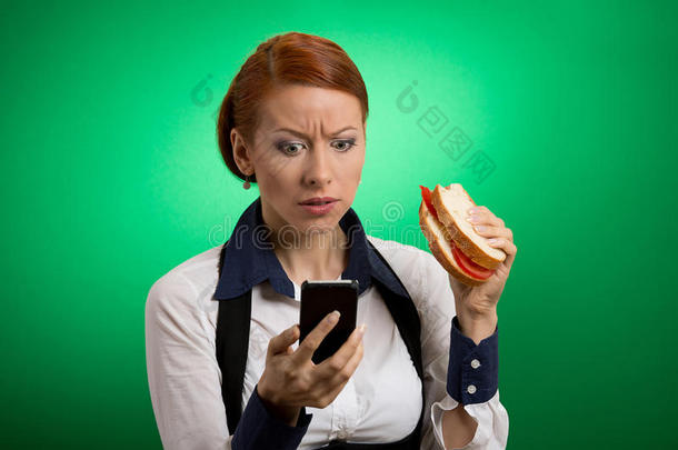 商业女人看手机吃三明治