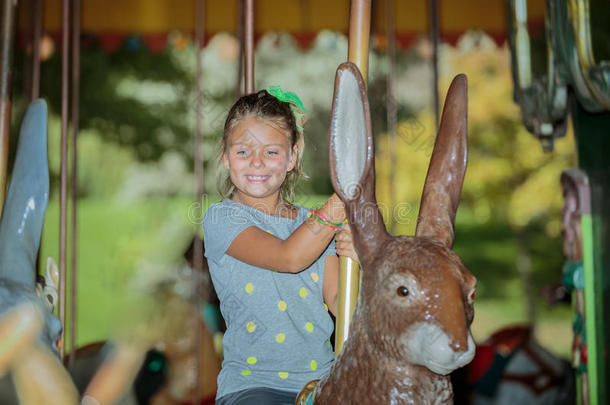 有趣的快乐小女孩骑复活节兔子旋转木马在阳光明媚的温暖的一天