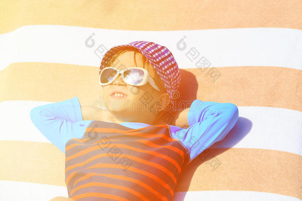 可爱的小男孩躺在夏天海滩的毛巾上