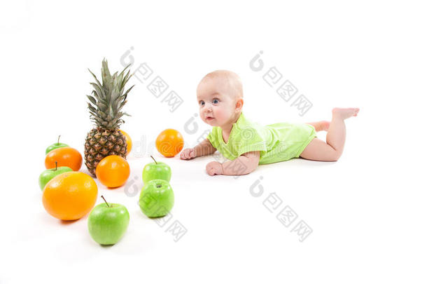 可爱的微笑婴儿躺在他的肚子里，在水果和看