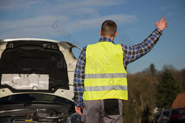 一个男人在她破车附近的路上寻求帮助