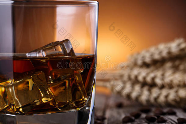 一杯加冰和小麦的威士忌放在木桌上。