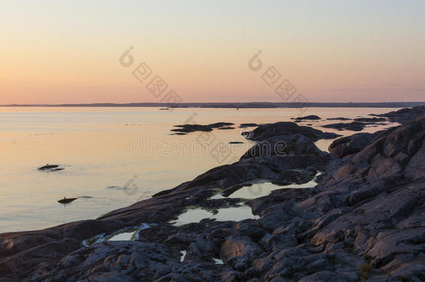 日落斯德哥尔摩群岛上有岩石池的悬崖