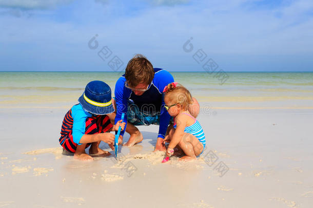 爸爸和孩子们在夏天的海滩上玩沙子