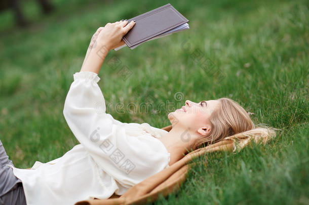 美丽的女孩在春天的花朵花园里看书