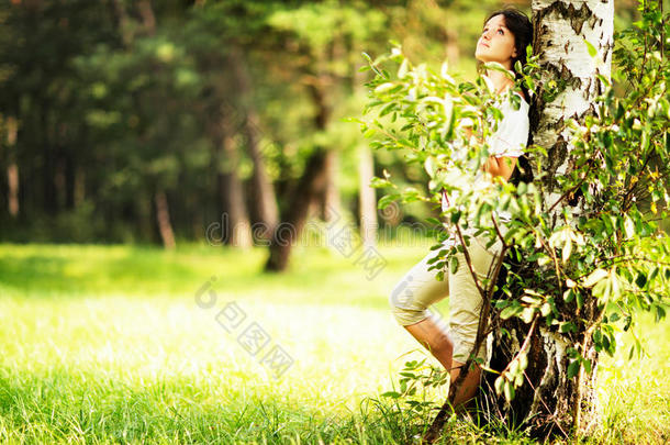 白种人的黑发少女站在一棵<strong>树</strong>附近，脸上有悲伤或<strong>梦幻</strong>的表情。 把目光移开。