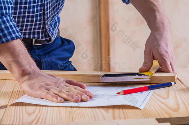木匠的手放在桌子上，上面有蓝图