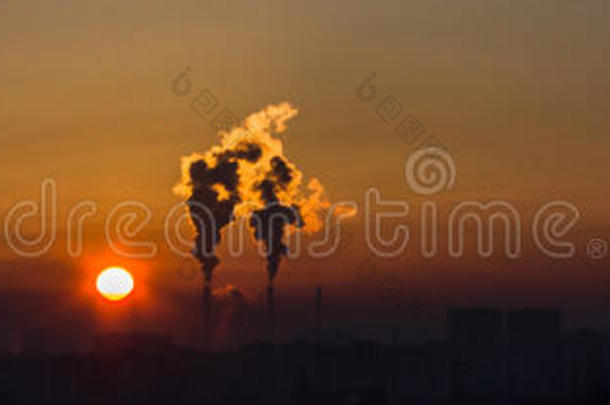 日落时工厂上空的烟囱和黑烟