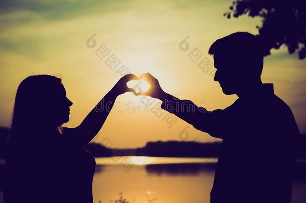 一对夫妇用手在湖岸上做心形。