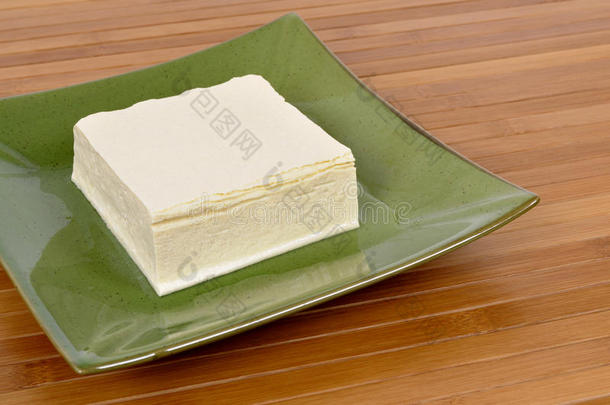 亚洲食物：绿色盘子上的新鲜豆腐块，木头背景