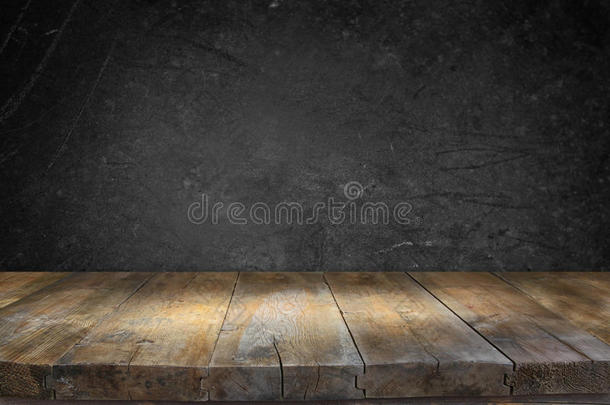 在黑色纹理背景前的灰色老式木板桌