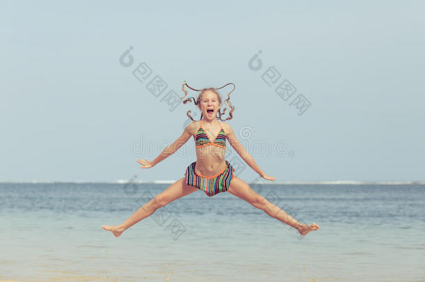 夏天在蓝色海岸的海滩上跳跃的少女