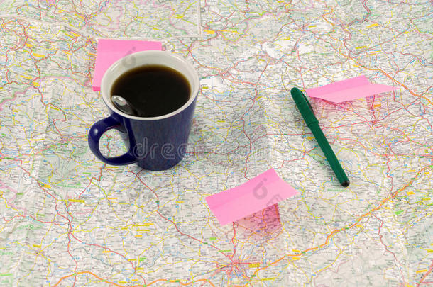 蓝色咖啡杯和纸，地图上有圆珠笔，为旅行做准备