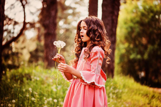 美丽的女孩穿着童话公主在夏天的森林里玩吹球