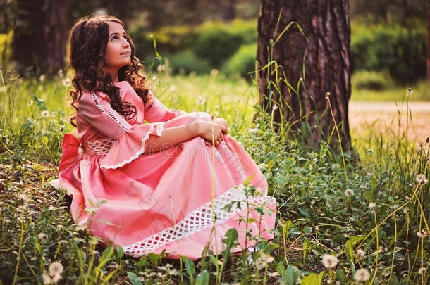 美丽的童女打扮成童话公主坐在夏天的森林里