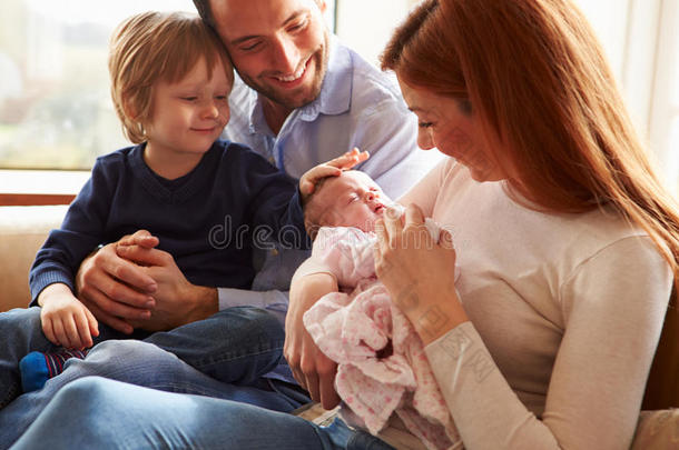 一家人抱着刚出生的婴儿坐在沙发上