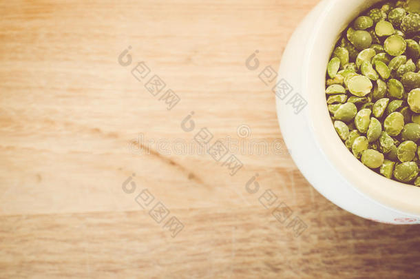 干裂的豌豆在一个白色的瓷罐在一个天然的木材冲浪