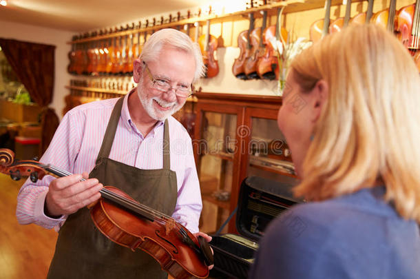 顾客离开小提琴在商店修理