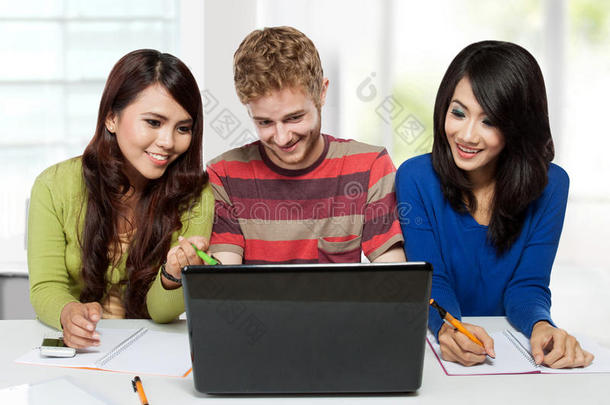 一群多样化的快乐学生一起使用笔记本电脑学习