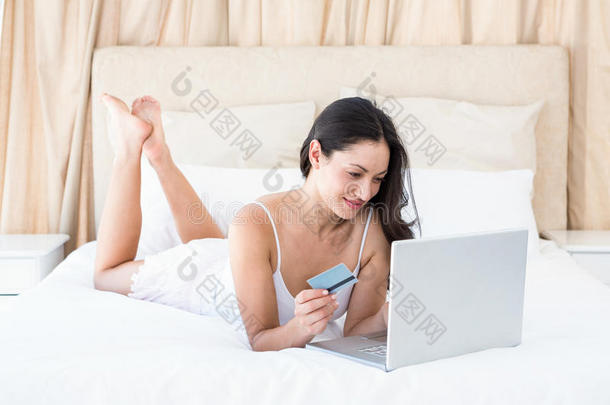 漂亮的黑发女人在床上网上购物