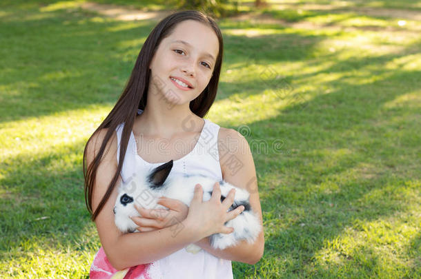 可爱的微笑少女抱着白色和黑色的小兔子