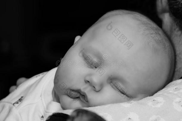 一个婴儿睡在他父亲的<strong>怀里</strong>