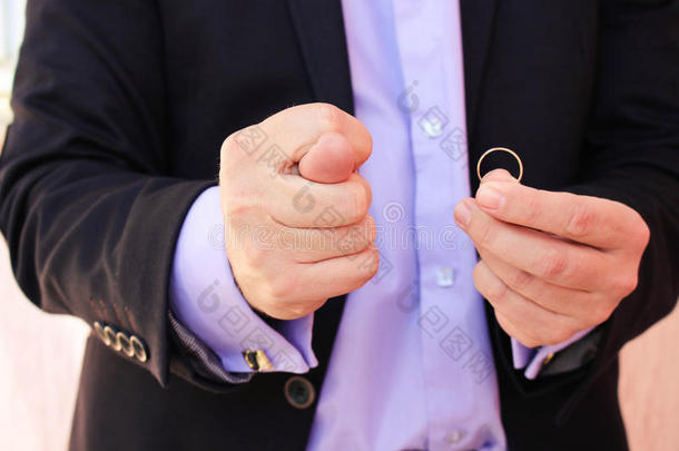 一个穿着西装的男人展示了菲戈，另一方面展示了一枚结婚戒指。 这个男人的概念不想结婚