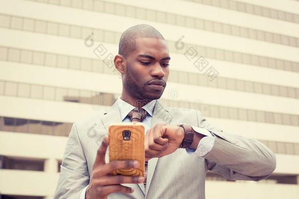 商人用<strong>手机</strong>发短信，看着他的<strong>手表</strong>