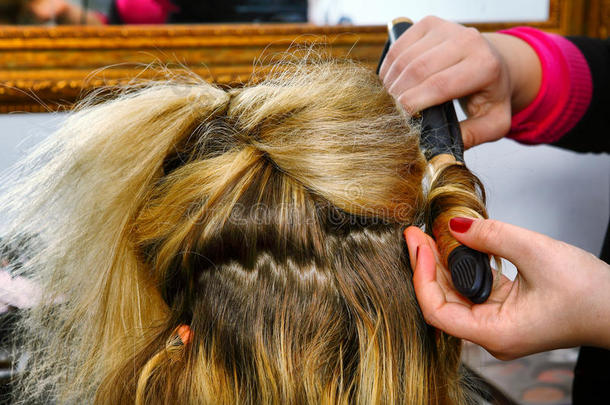 头发梳妆台的手用卷发钳做卷发，特写照片