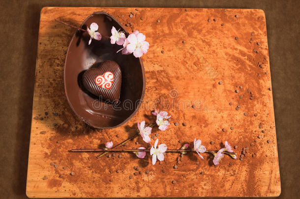复活节巧克力鸡蛋与一个惊喜的装饰心，洒上可可粉，巧克力片和杏仁花。