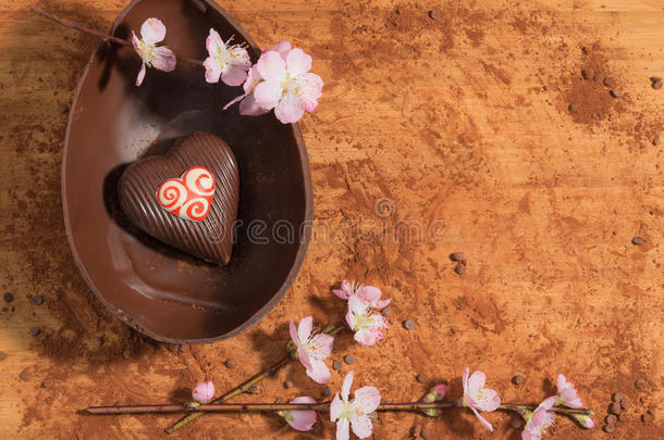 复活节巧克力鸡蛋与一个惊喜的装饰心，洒上可可粉和杏仁花。