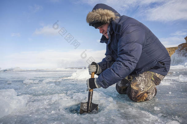 一个拿着铲子的人把湖里的冰裂开了