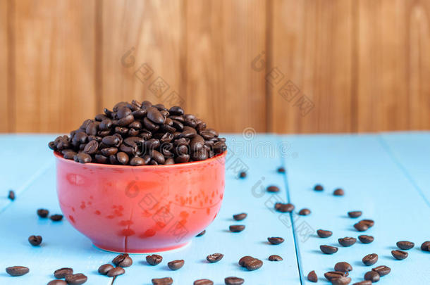 蓝色桌子上红色碗里的咖啡豆和深色的咖啡豆