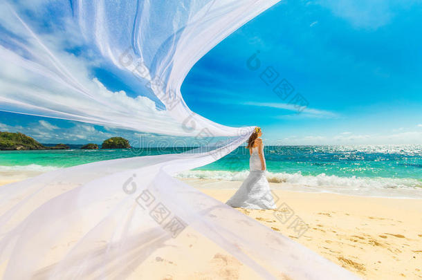 美丽的未婚妻穿着白色婚纱和白色的大火车，日落时站在海边