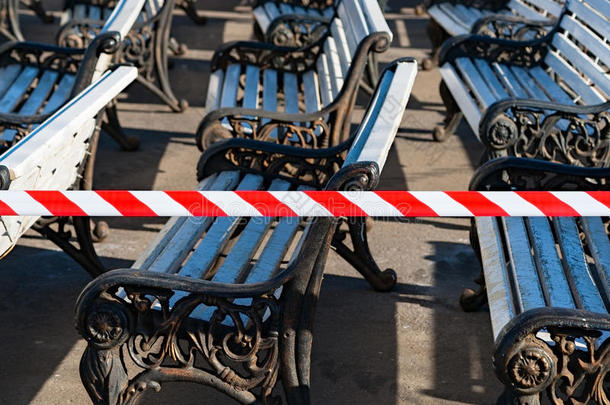 公共公园里的长凳正在为即将到来的夏季做准备。 警告磁带警告人们长凳仍然是di