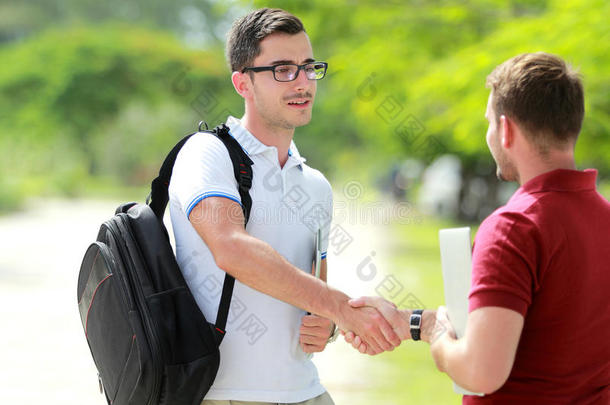 带眼镜的大学生在大学公园和他的朋友见面