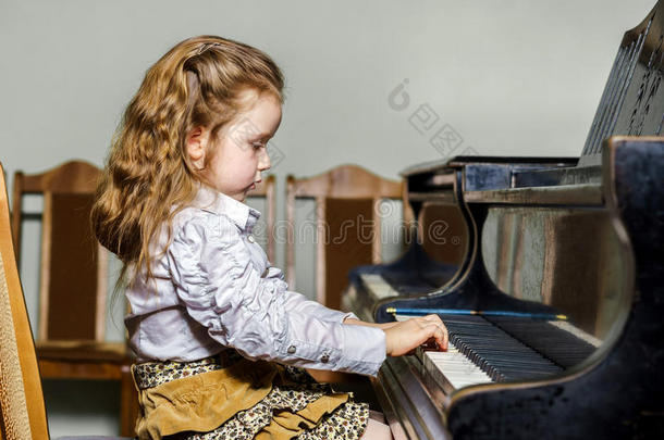 可爱的小女孩在音乐学校弹大钢琴