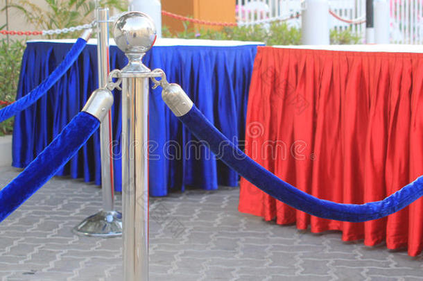 人群控制屏障，蓝色天鹅绒绳和接待台覆盖红色和蓝色丝绸条纹