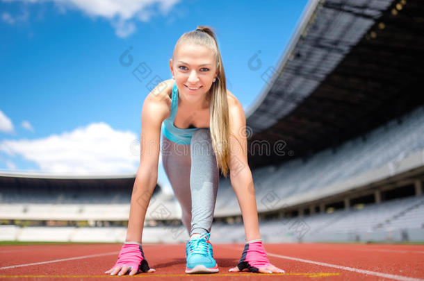 健身<strong>运动</strong>女孩准备在体育场的<strong>运动</strong>跑<strong>道</strong>上跑步。 健康和<strong>运动</strong>的生活方式与年轻女孩跑步