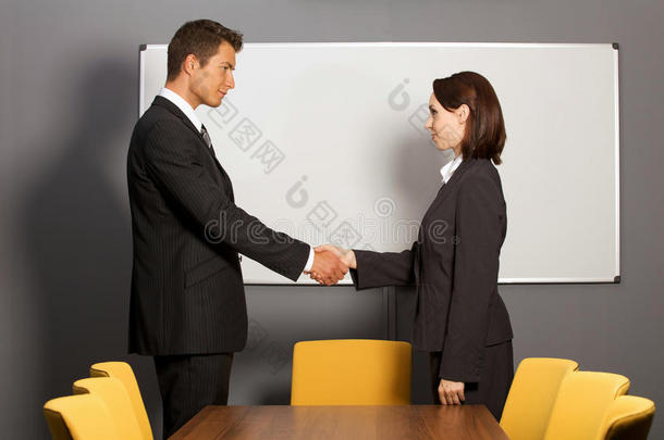 商人和女人在办公室里握手，微笑着