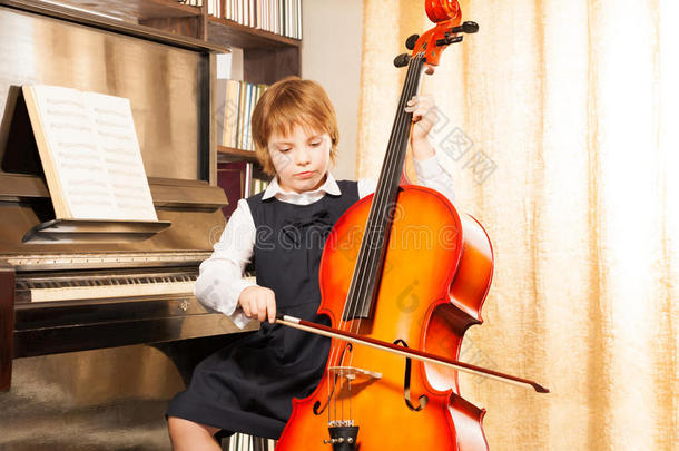 穿着校服的漂亮女孩在大提琴上演奏