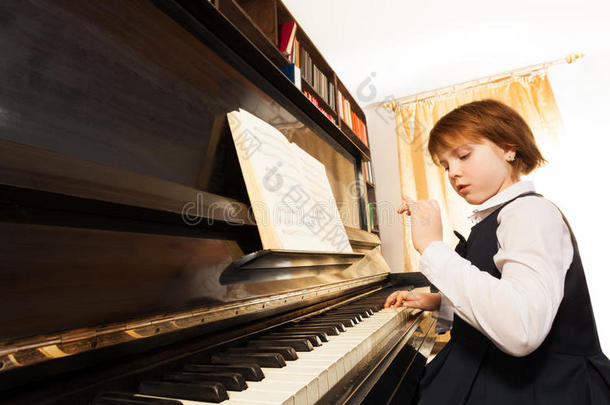集中的小女孩穿着制服弹钢琴