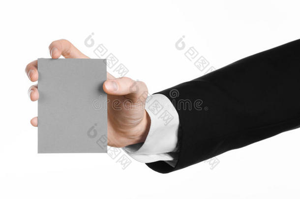 商业和广告主题：穿着黑色西装的男人手里拿着一张灰色的空白卡，在工作室的白色背景上隔离